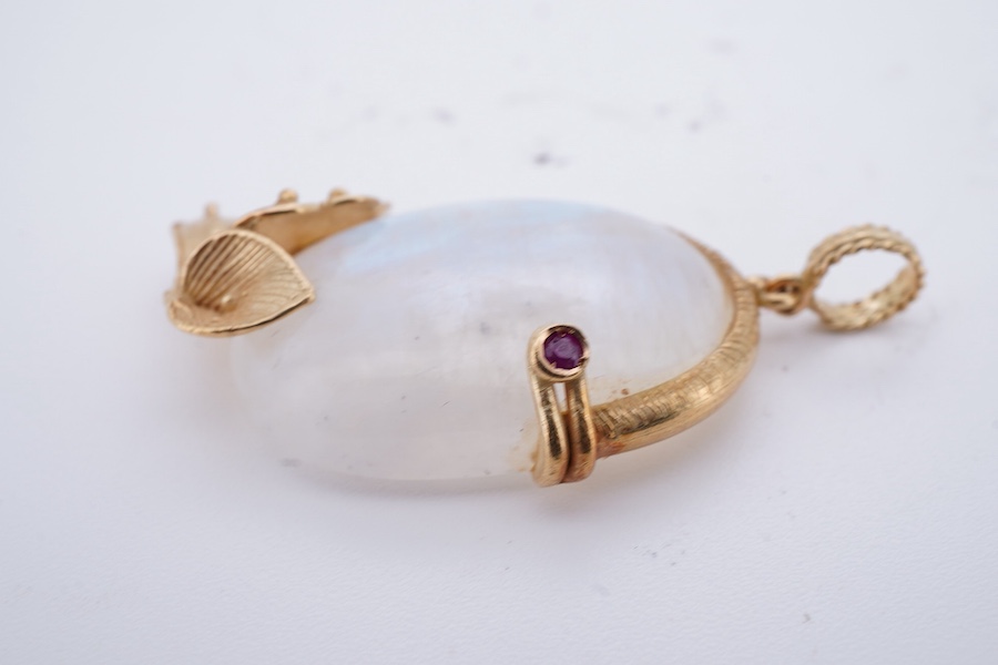 A gold and moonstone pendant, set with a moonstone cabochon, to a textured gold mount of foliate design accented with a collet-set circular-cut ruby, length 4.5cm, gross weight approximately 12 grams
